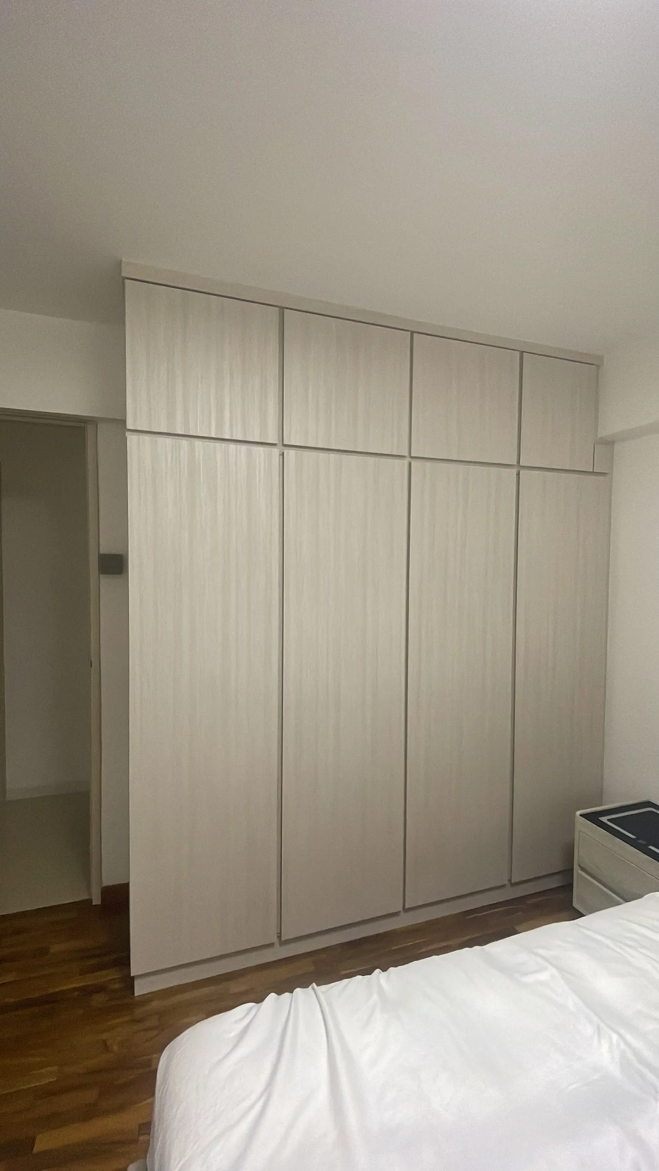 A full-height built-in wardrobe run resurfaced in a pale woodgrain.