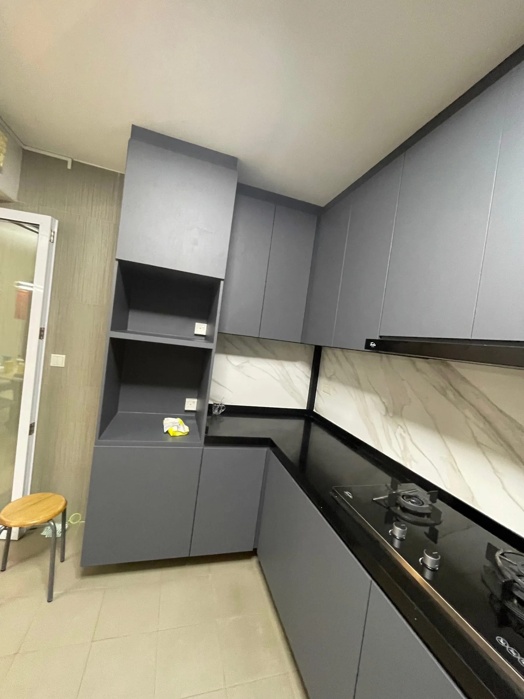 A Punggol HDB kitchen with grey wrapped cabinet fronts and a marble-effect backsplash.