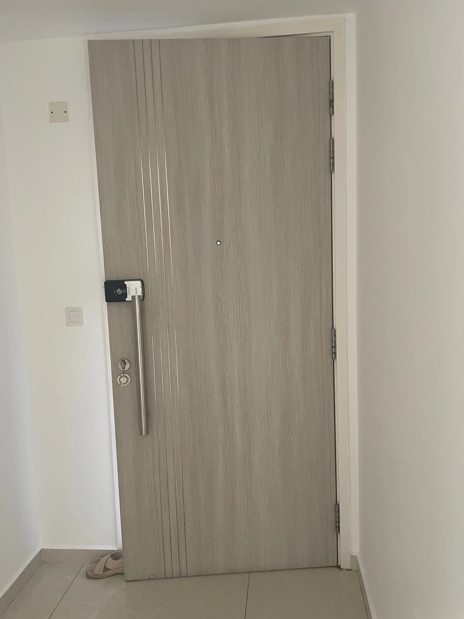 A main door wrapped in a light oak woodgrain, with the frame taken to match.